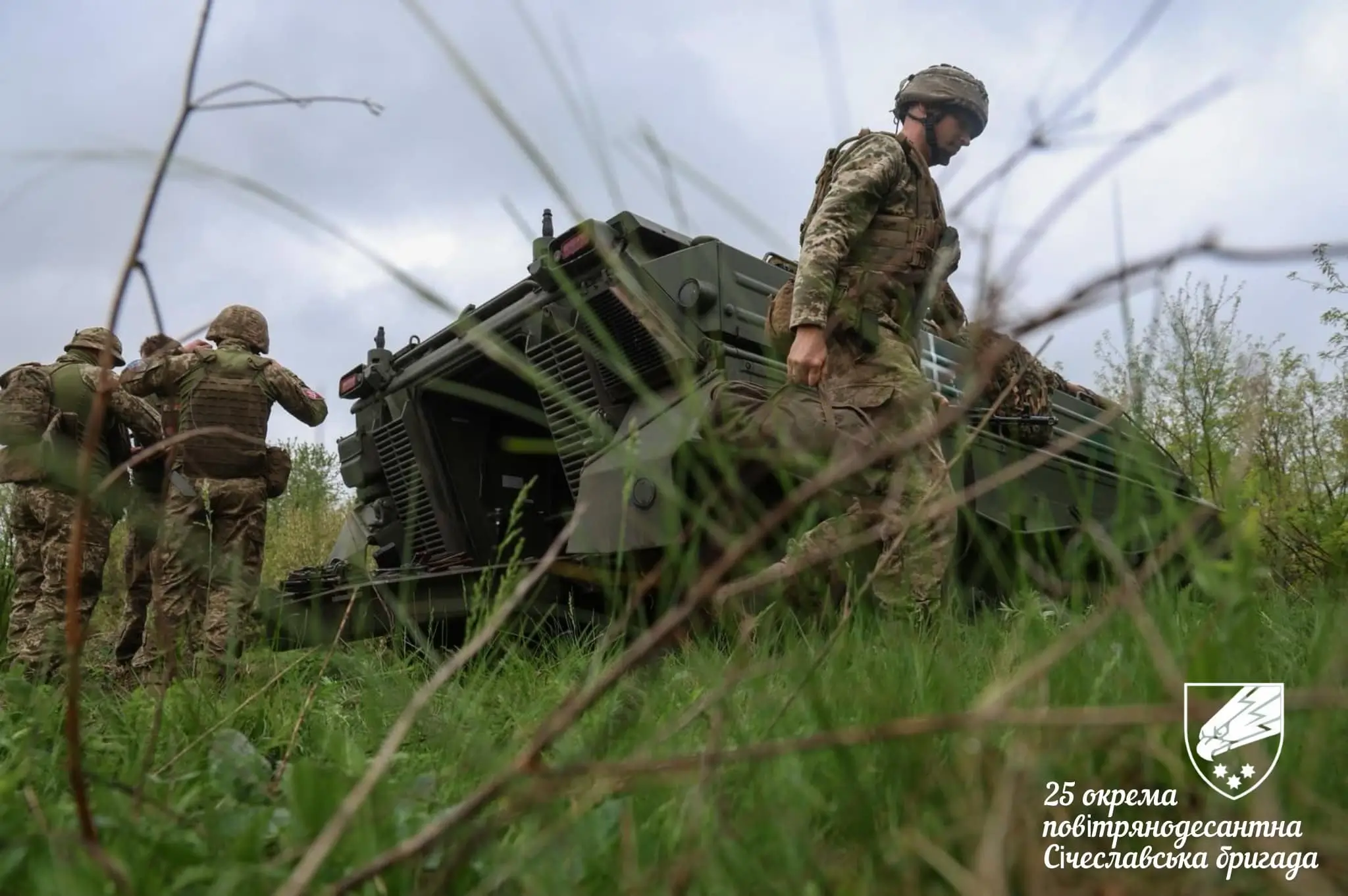 Ukrainian soldiers stand in front of and behind a Marder 1A3