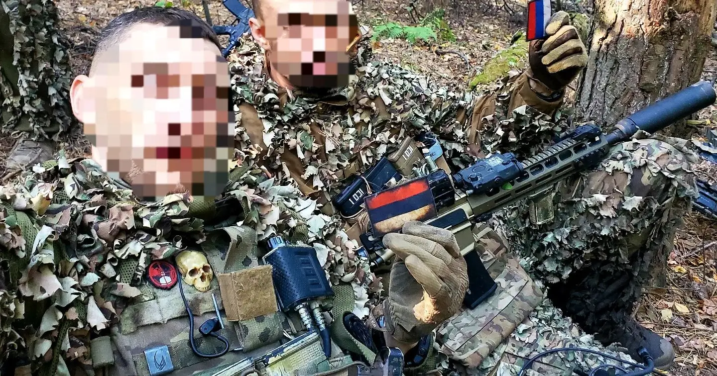 Two Ukrainian soldiers with MK 556 assault rifles showing off badges looted from neutralised enemies