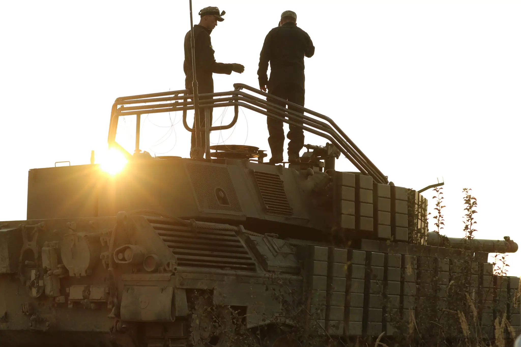 Soldiers standing on a Leopard 1A5 with plenty of additional reactive armour and an installation for a drone net